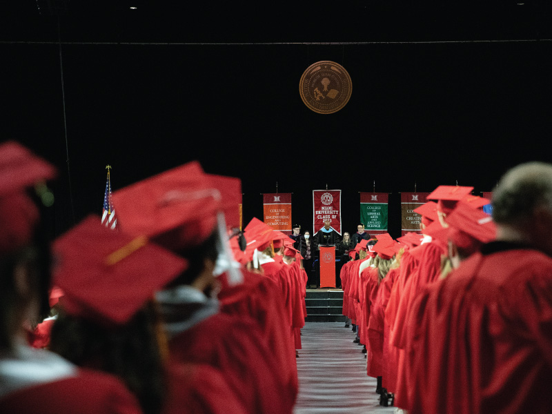 Graduates in their cap and gowns walking at commencement.