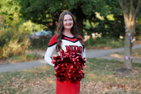 Avery Pennington, Nursing major in her Miami cheerleading uniform holding red, and black pom poms.