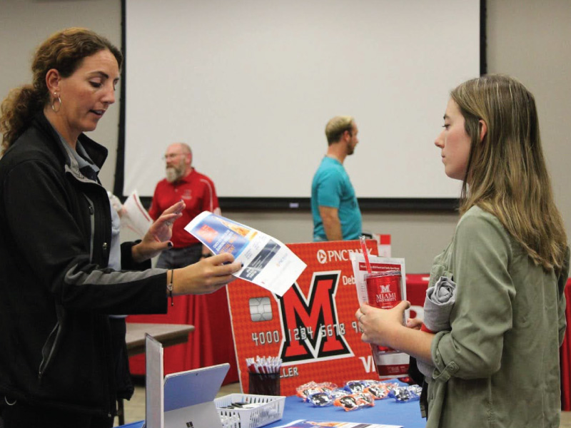 A student at orientation visiting a booth during the information fair to get information about a program.