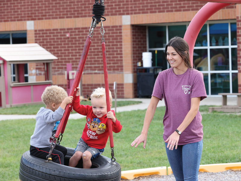 Work+ student pushing 2 children on a tire swing at the YMCA.