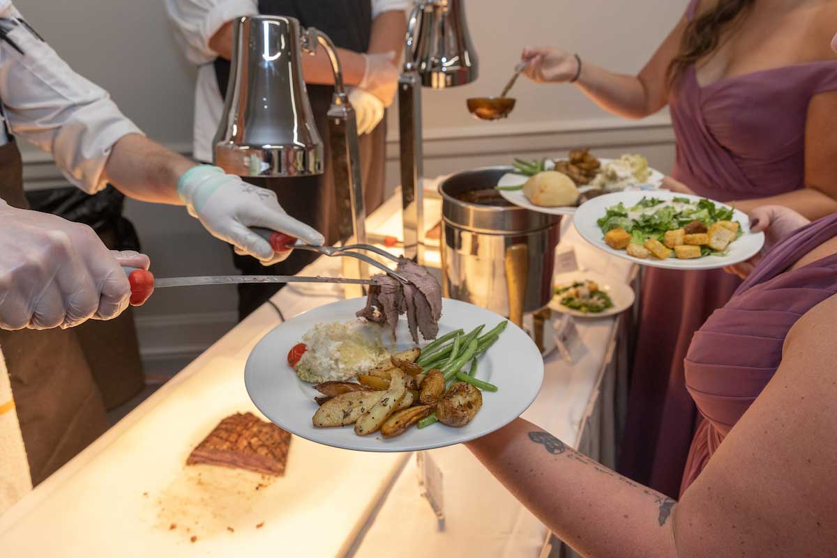 a person placing carved beef on another person's plate